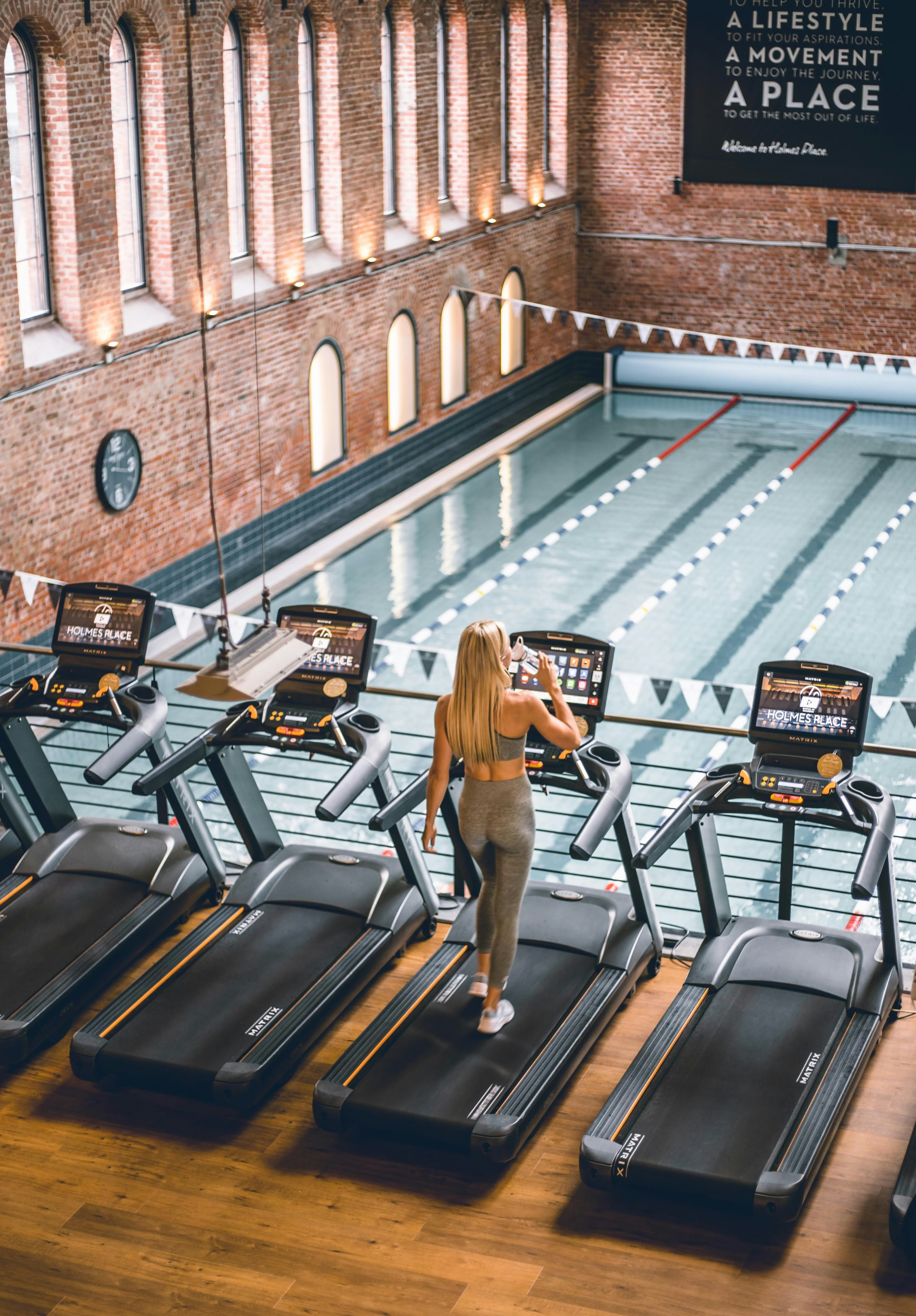 Runner training on treadmill with pool in background
